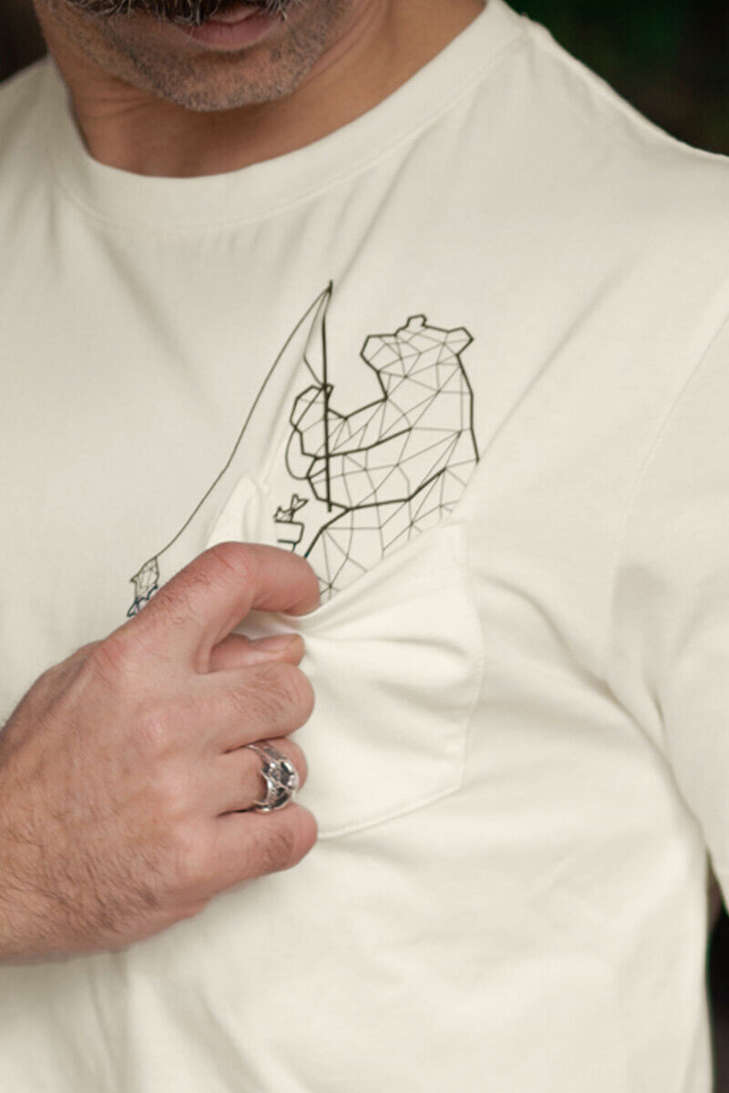 Angler mit einer gefangenen Forelle am Wasser, umgeben von Natur.