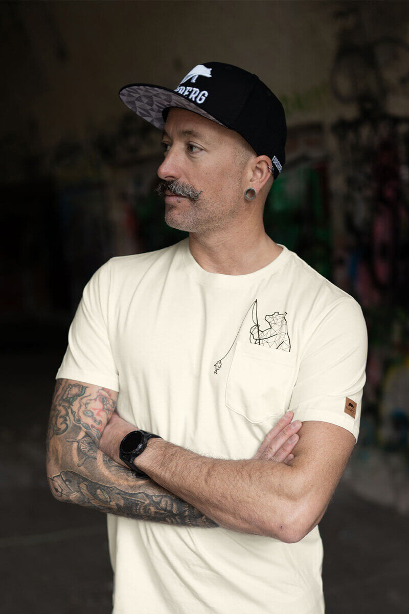 Angler hält eine große Forelle am Ufer eines Gewässers.