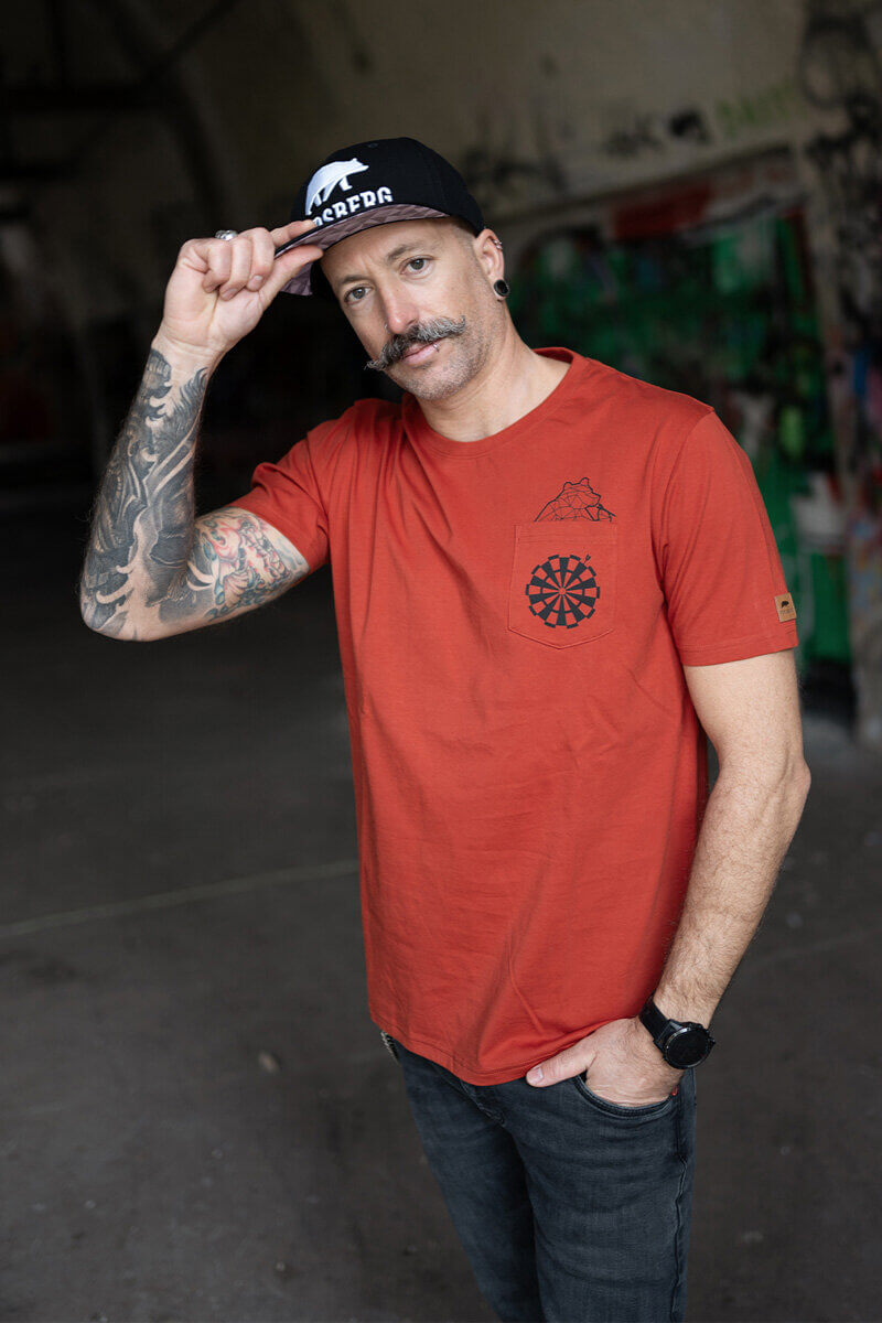 Dartscheibe mit Dartpfeilen in einem dunklen Raum.